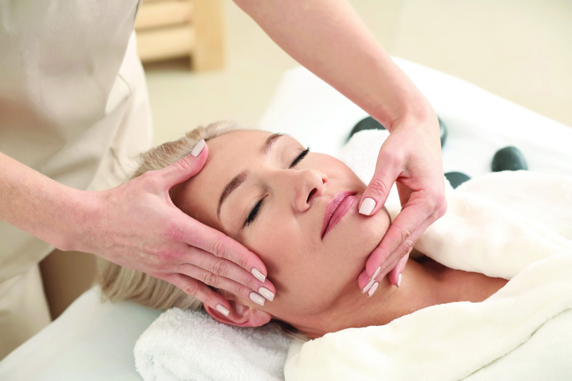 Mature woman receiving face massage in beauty salon Mature woman receiving face massage in beauty salon